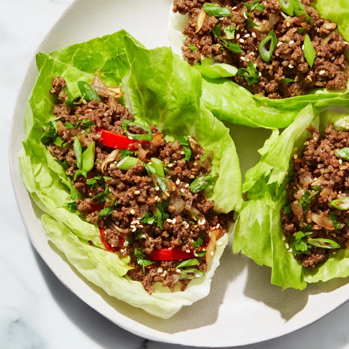 A plate of delicious Beef Lettuce Wraps, featuring a steaming meat mixture in cool lettuce cups.