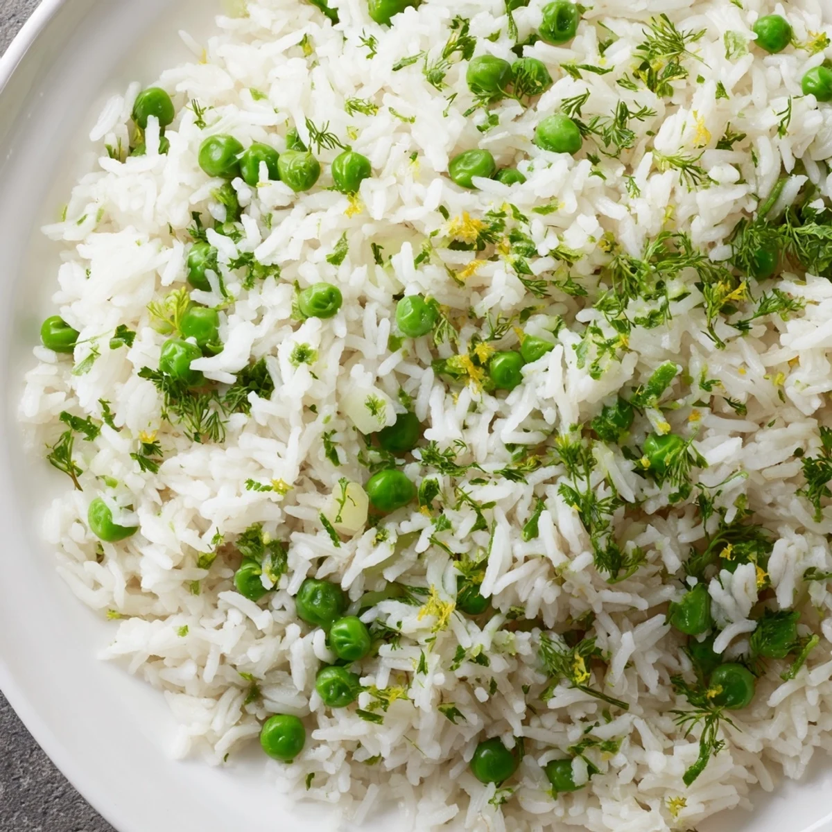 Fluffy Lemon Herb Rice Pilaf with bright green peas steaming in a white serving bowl.