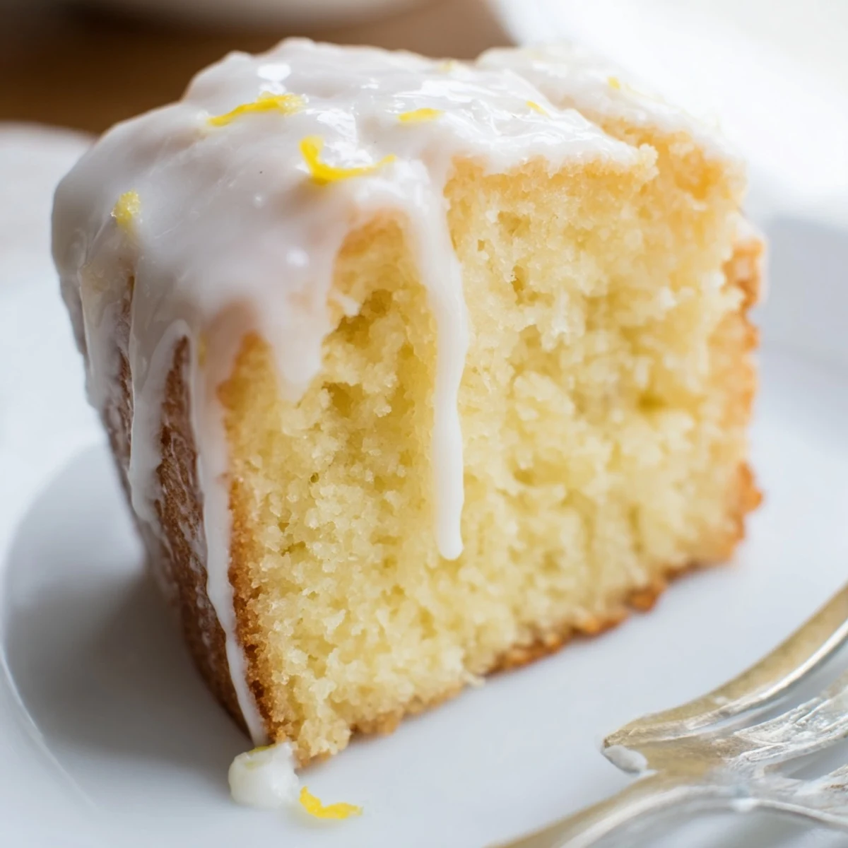 Thick lemon glaze dripping down the sides of a freshly baked Lemon Loaf.