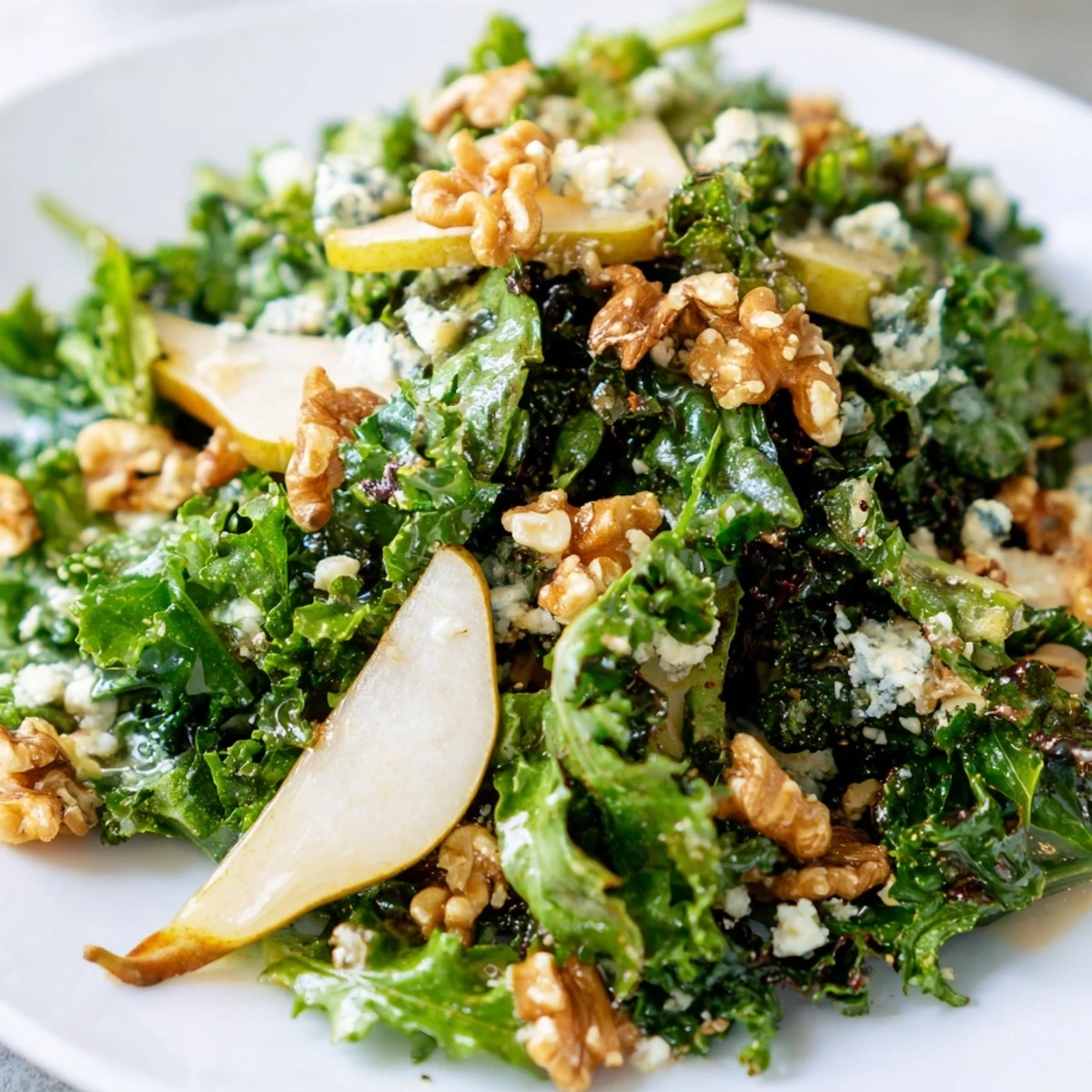 Freshly made Winter Green Salad with Pears topped with walnuts and a honey-Dijon vinaigrette, served in a white bowl.