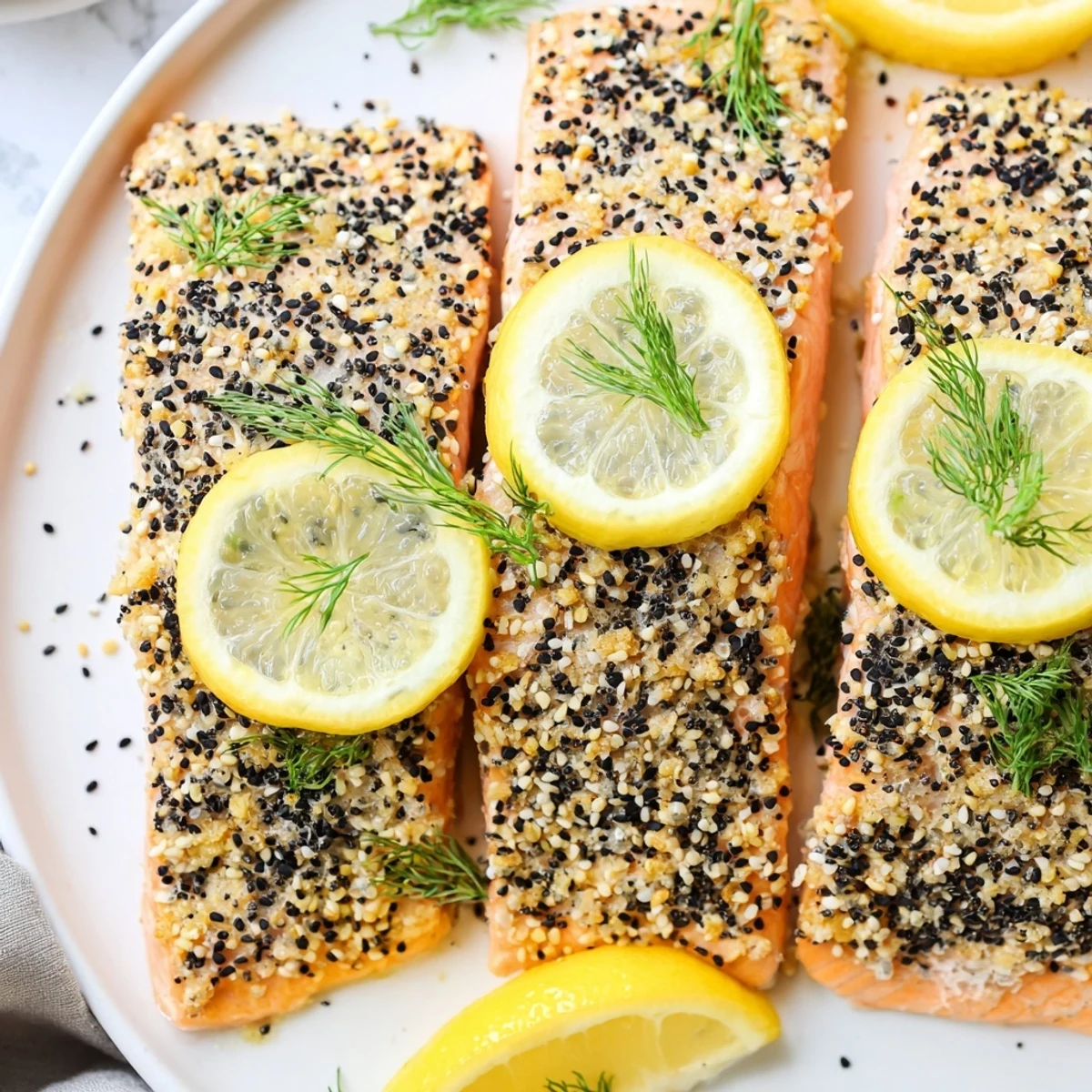 Fresh dill sprinkled over the finished Baked Salmon with Everything Bagel Seasoning, served hot alongside a colorful salad for a healthy meal.