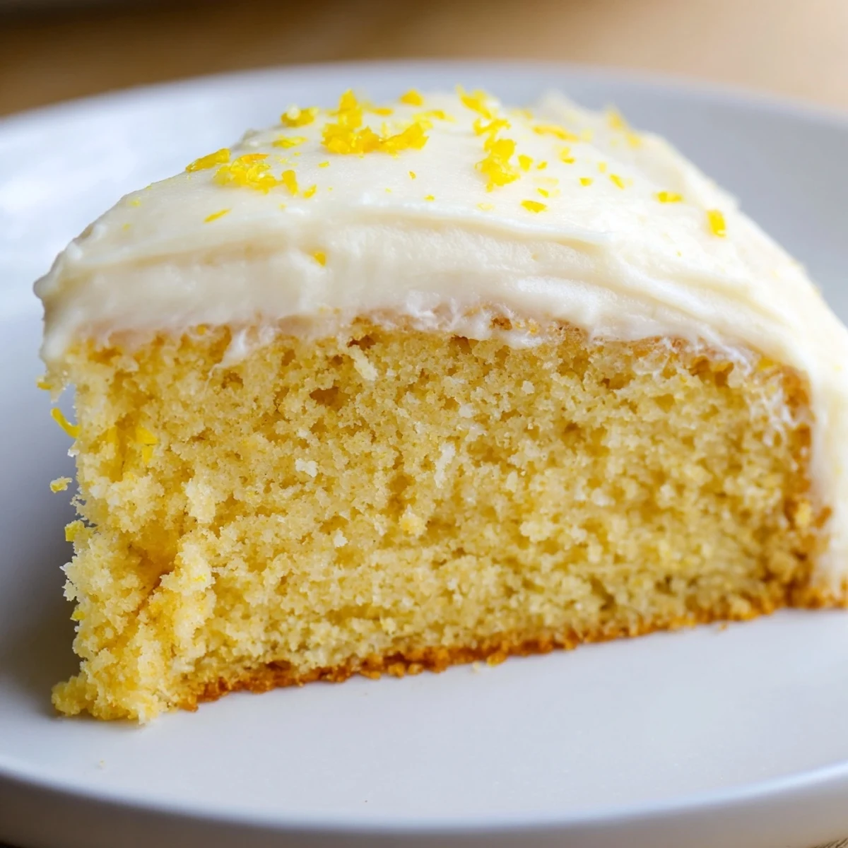 A fresh slice of Lemon Cake with Frosting shows moist yellow crumb and creamy white frosting.