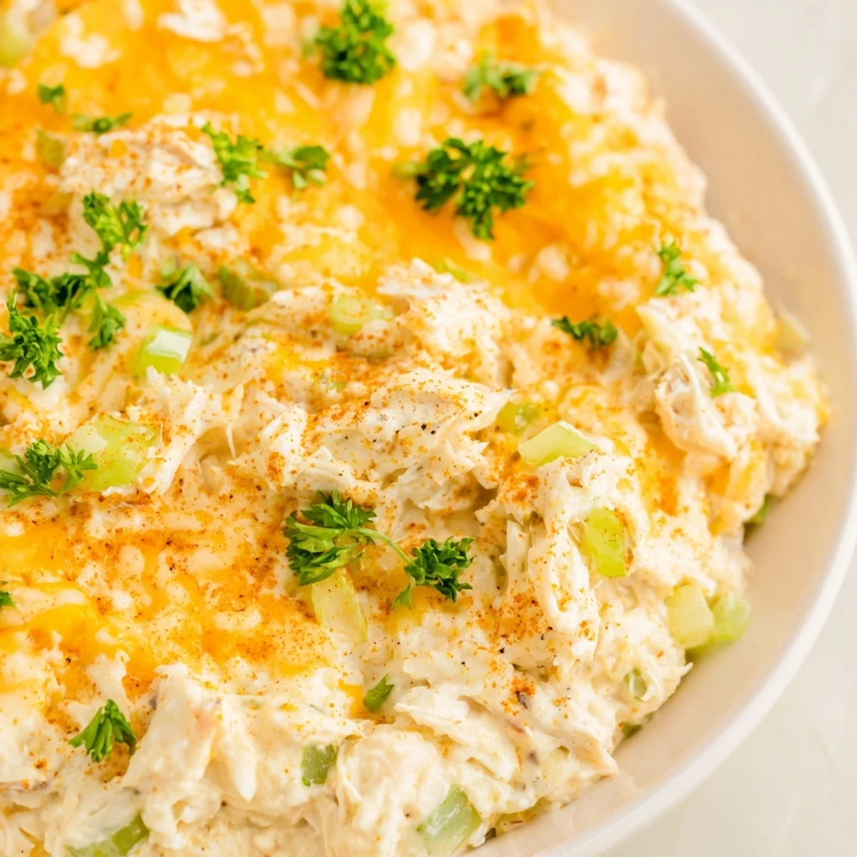 Warm Cajun Crab Dip in a ceramic dish, surrounded by a rustic spread of crackers and fresh herbs.