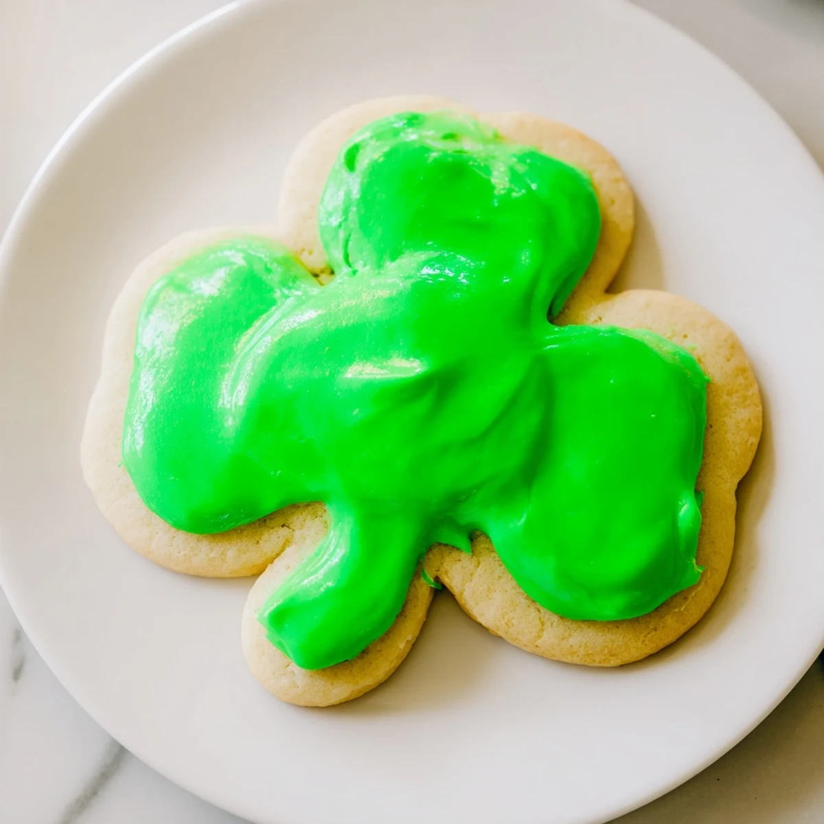 A close-up of Shamrock Sugar Cookies with Green Icing, showing a buttery crumb and bright green drizzle.