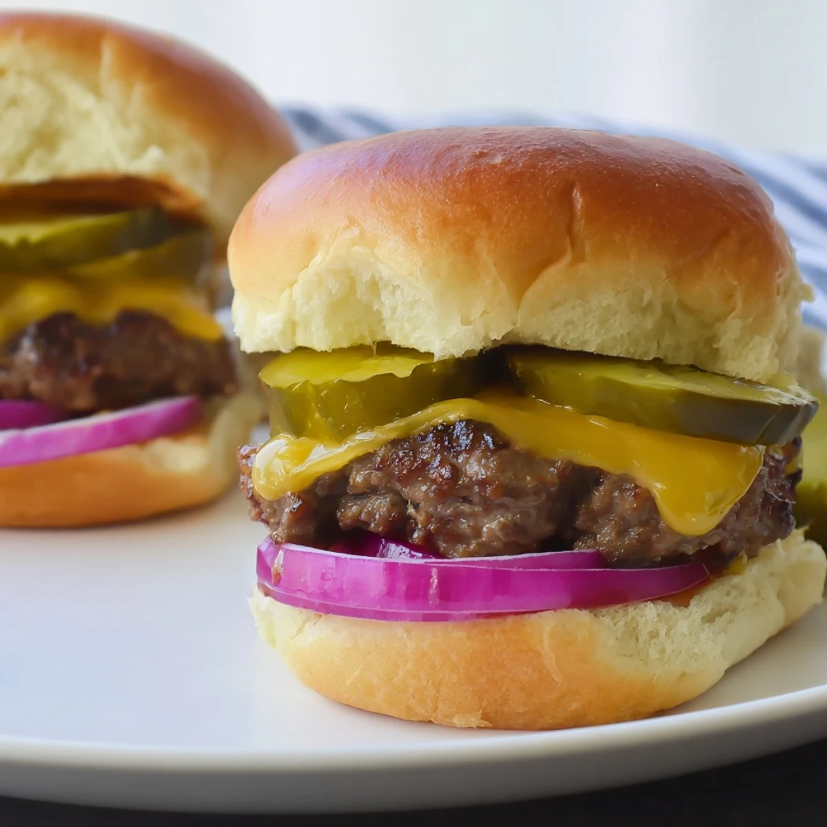Freshly grilled mini beef patties topped with tangy dill pickles for a game day snack.