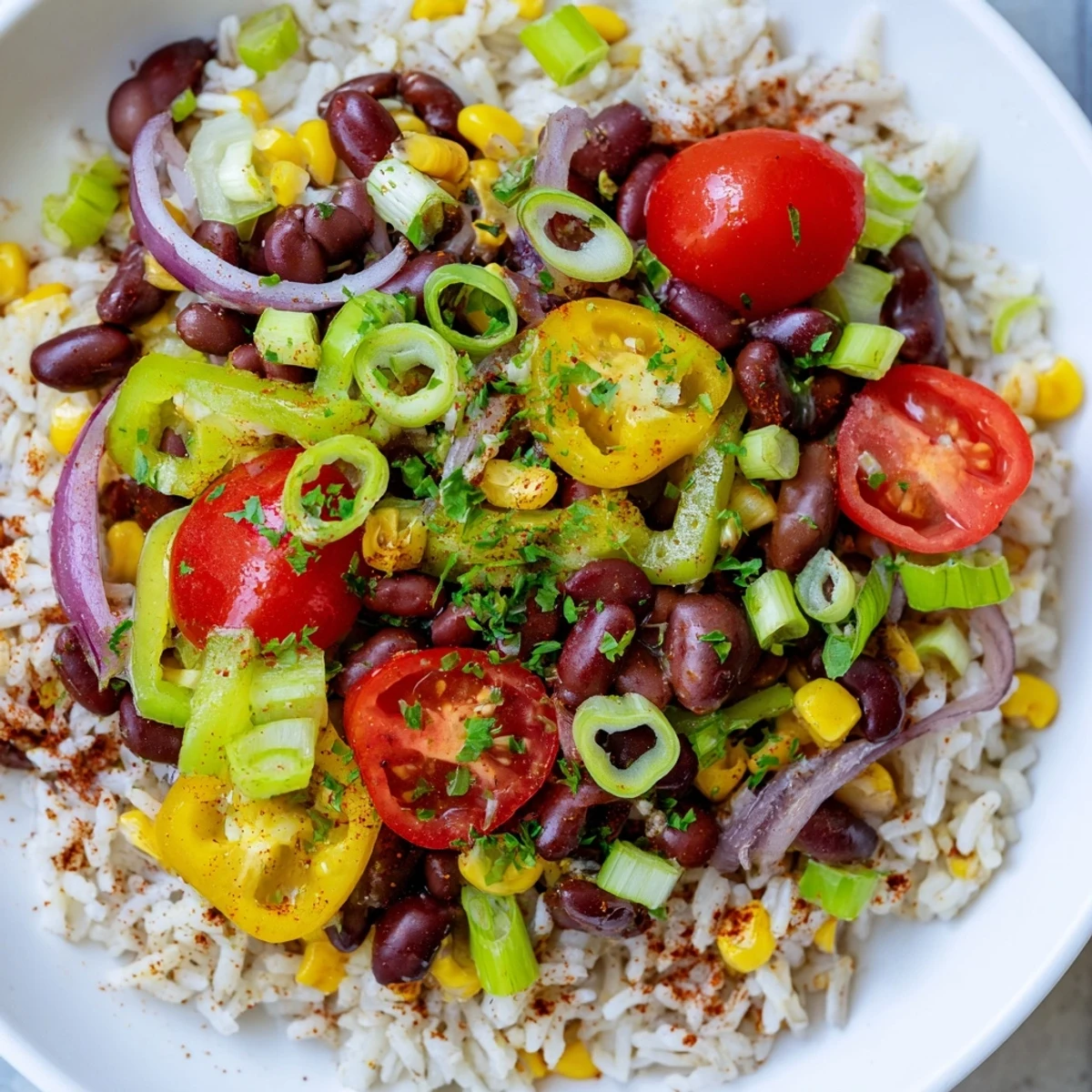 Colorful Mardi Gras Veggie Rice Bowl with bell peppers, beans, and a dash of hot sauce on a festive plate.