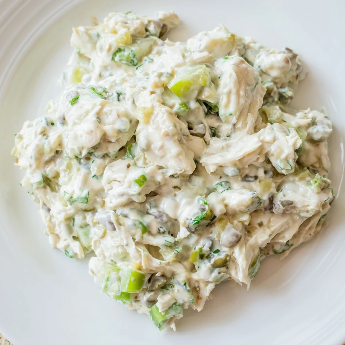 Creamy remoulade sauce topped with tender crab meat, celery, and capers, ready to be served as a zesty dip or spread.