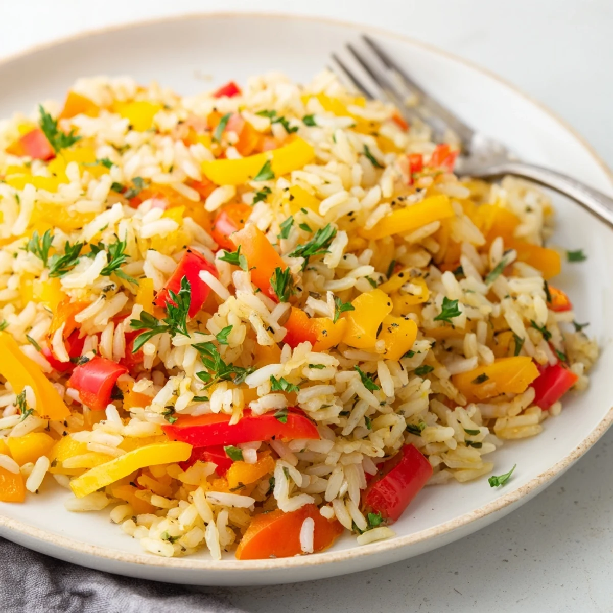 A vibrant bowl of Rice Pilaf with Peppers and Onions, featuring fluffy golden grains mixed with tender red and yellow peppers and sautéed onions, garnished with fresh green parsley.