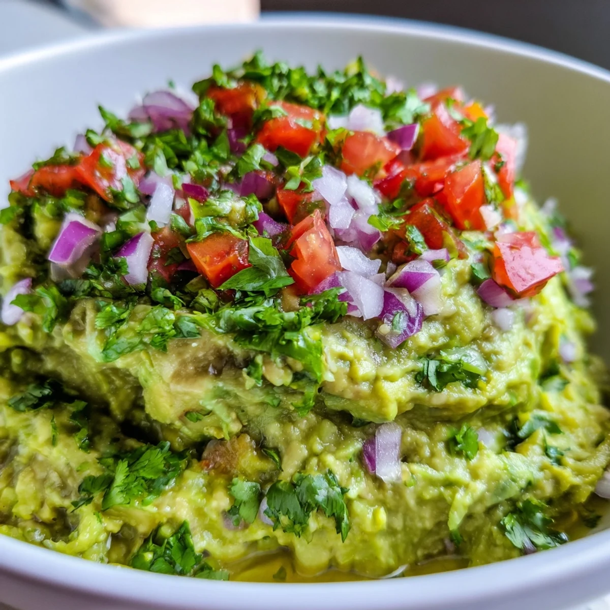 A close-up of creamy guacamole with chunky pico de gallo served in a rustic bowl with tortilla chips.