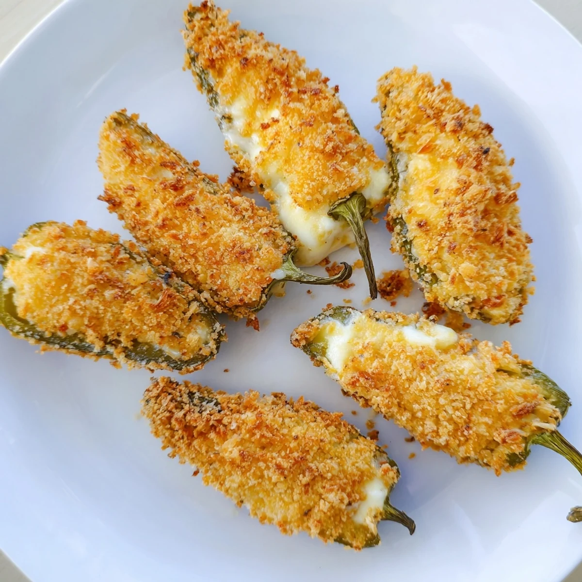 Close-up of a bitten Spicy Jalapeno Poppers with Cream Cheese showing gooey melted filling and crumbs.
