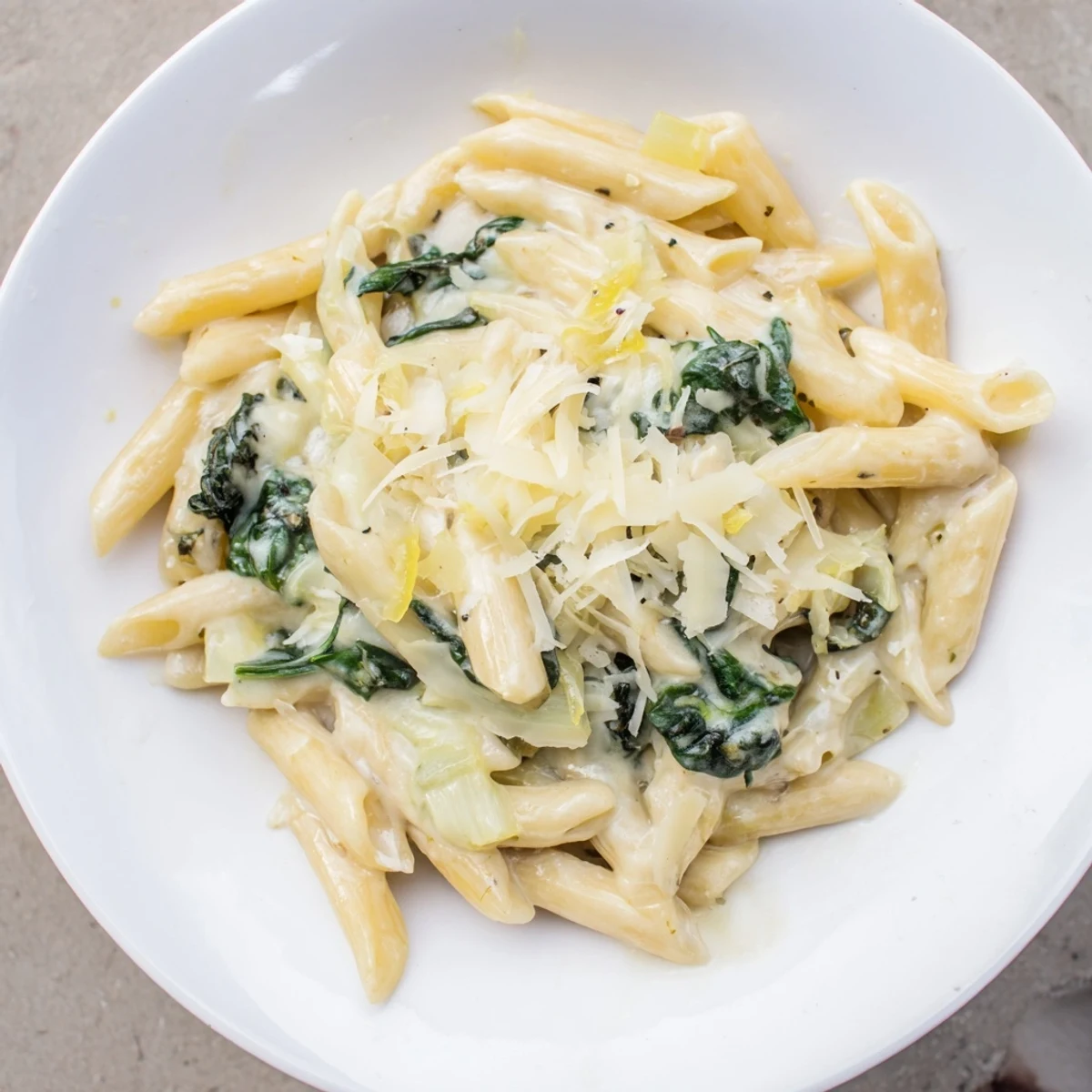 Steaming plate of Creamy Spinach Pasta with Garlic served alongside a crisp green salad and wine.