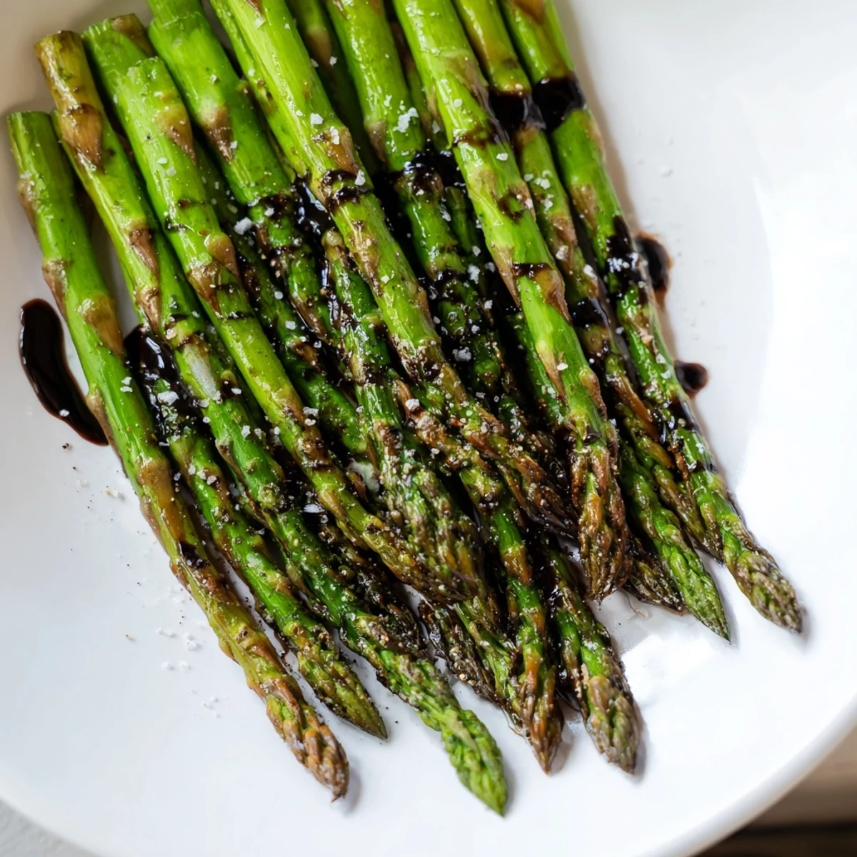 Golden-brown roasted asparagus spears glisten with a sweet balsamic reduction on a white platter, ready to serve alongside grilled chicken or fish.
