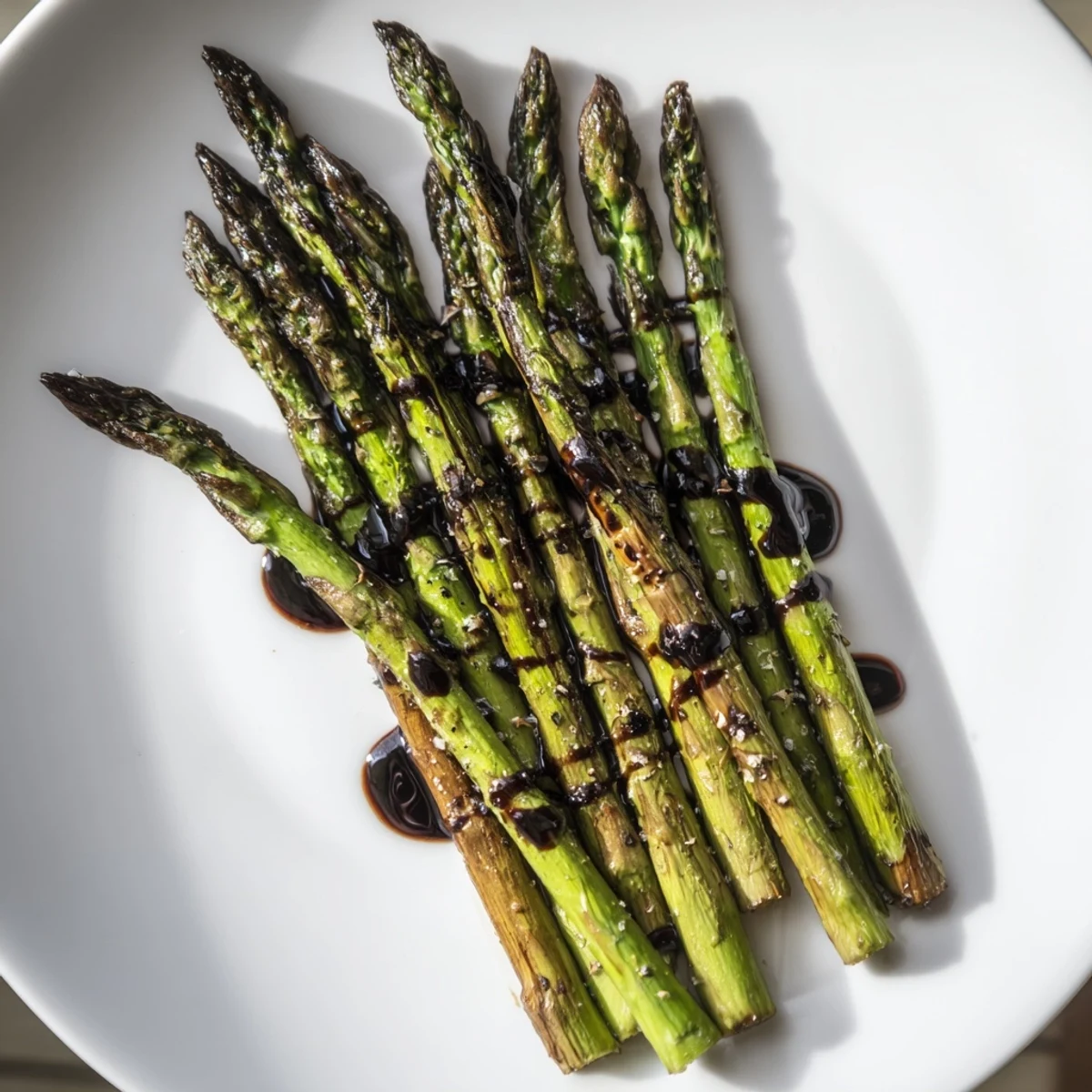 Fresh asparagus roasted with olive oil, salt, and pepper is drizzled with a tangy balsamic glaze in this easy vegan side dish.