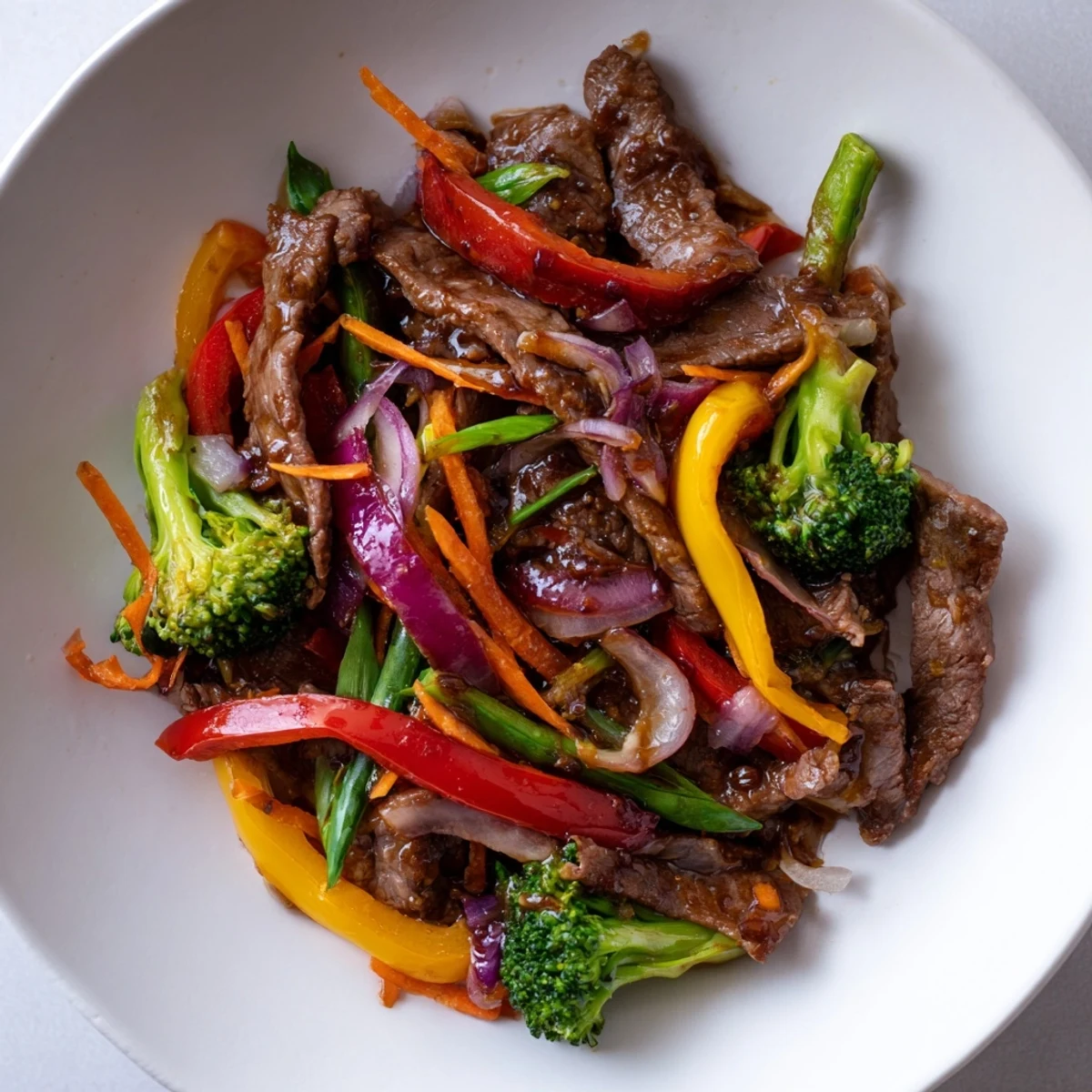 An overhead view of Spicy Beef Stir Fry with Mixed Vegetables, tossed in a glossy chili garlic sauce and garnished with fresh sesame seeds.