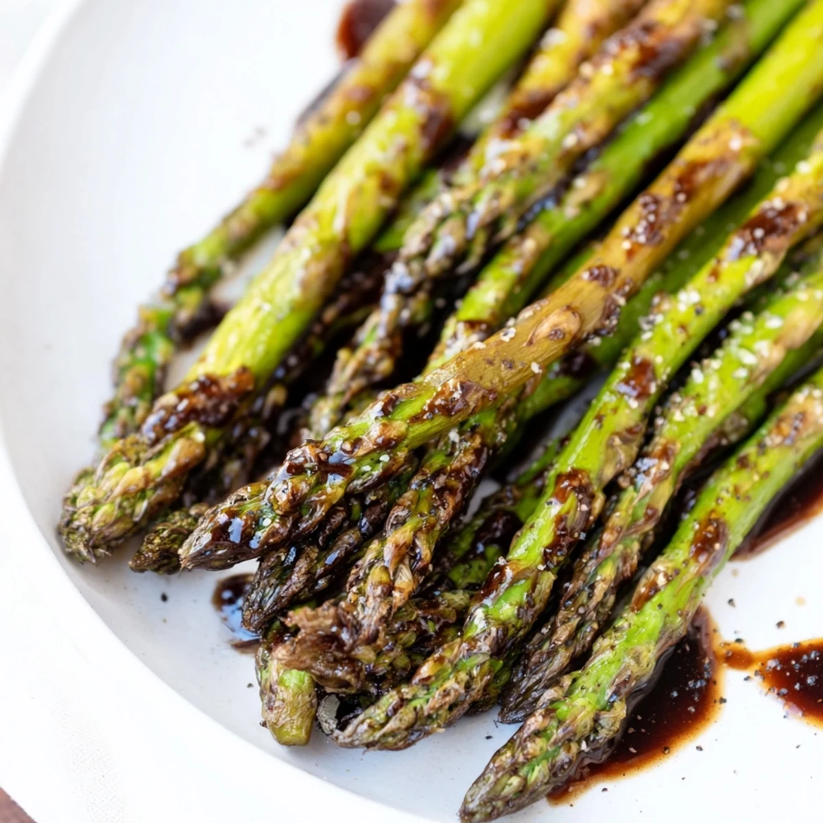 Roasted Asparagus with Balsamic Glaze garnished with pine nuts, paired with grilled tofu for a vegan side dish.