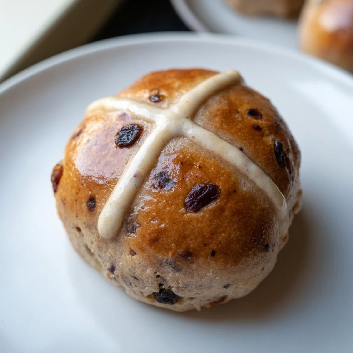 Freshly baked Easter Hot Cross Buns with a golden glaze, dusted with flour on a rustic wooden board.
