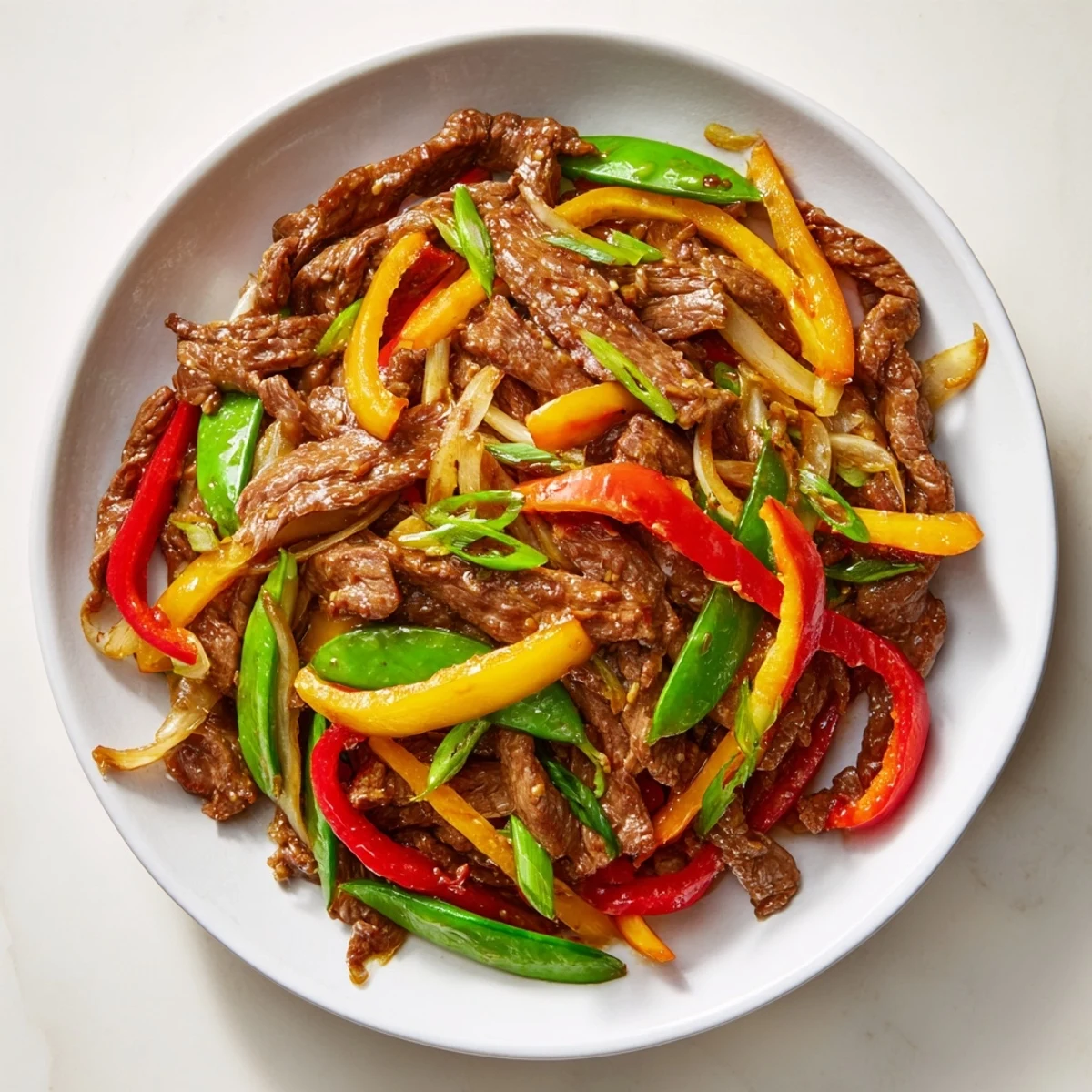 Bright serving platter of Spicy Beef Stir Fry with Vegetables next to fluffy white jasmine rice and chopsticks.
