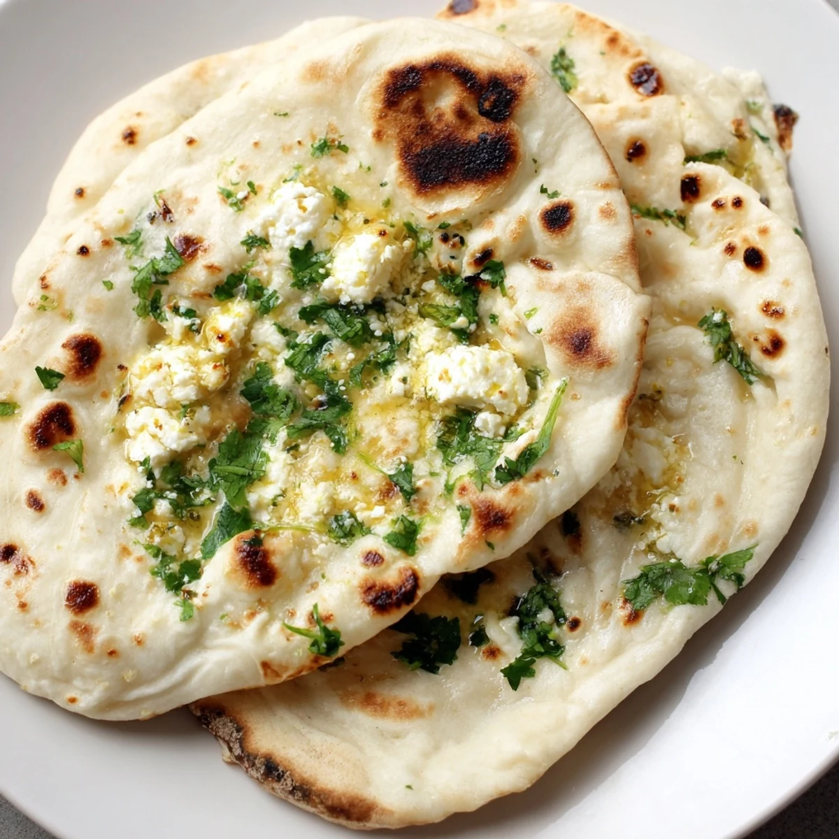 Golden-brown Cottage Cheese Garlic Naan brushed with garlic butter, fresh cilantro, and resting on a rustic board, served alongside a bowl of curry.