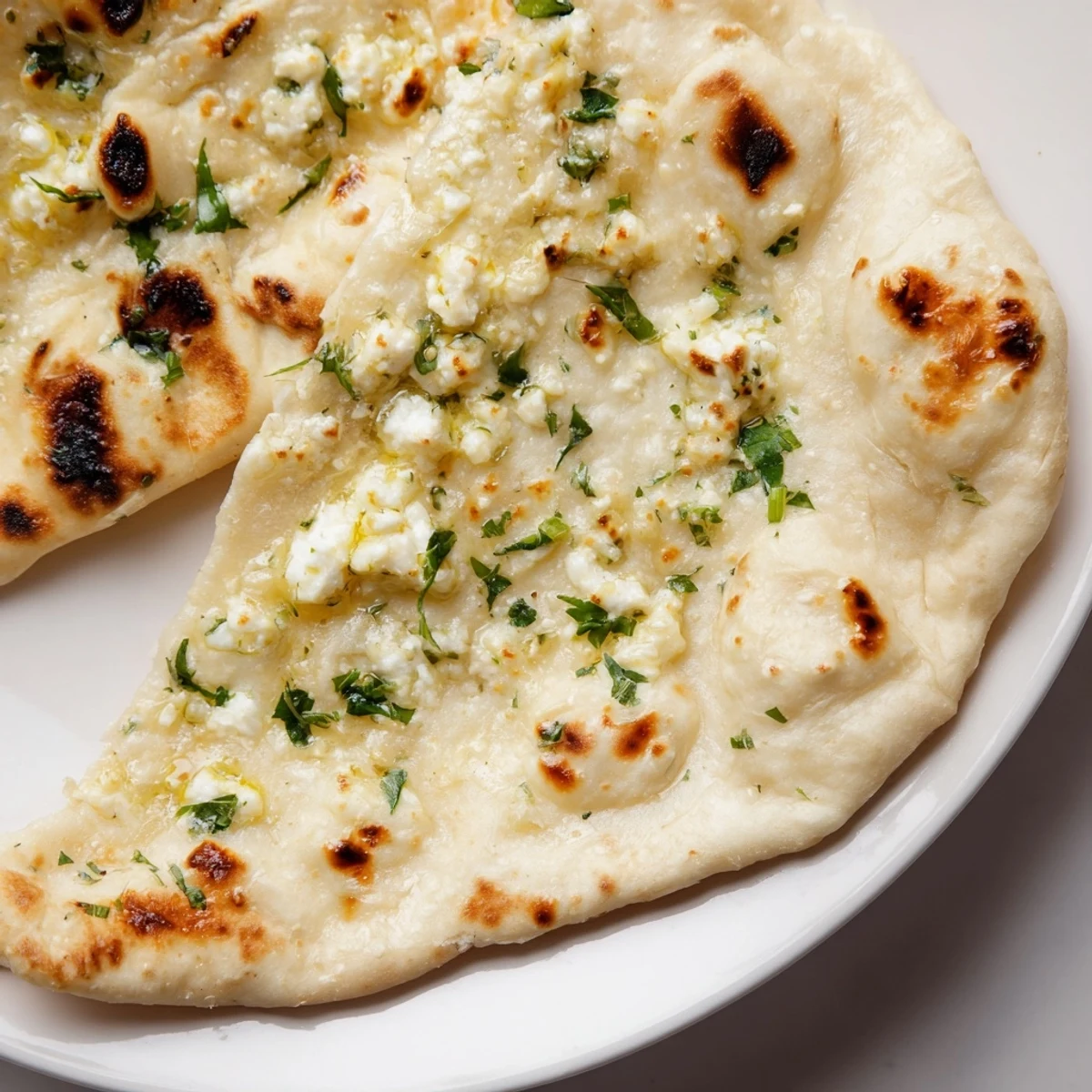 Freshly baked Cottage Cheese Garlic Naan with melted cottage cheese filling, soft and pillowy texture, paired with raita and dal on a wooden platter.