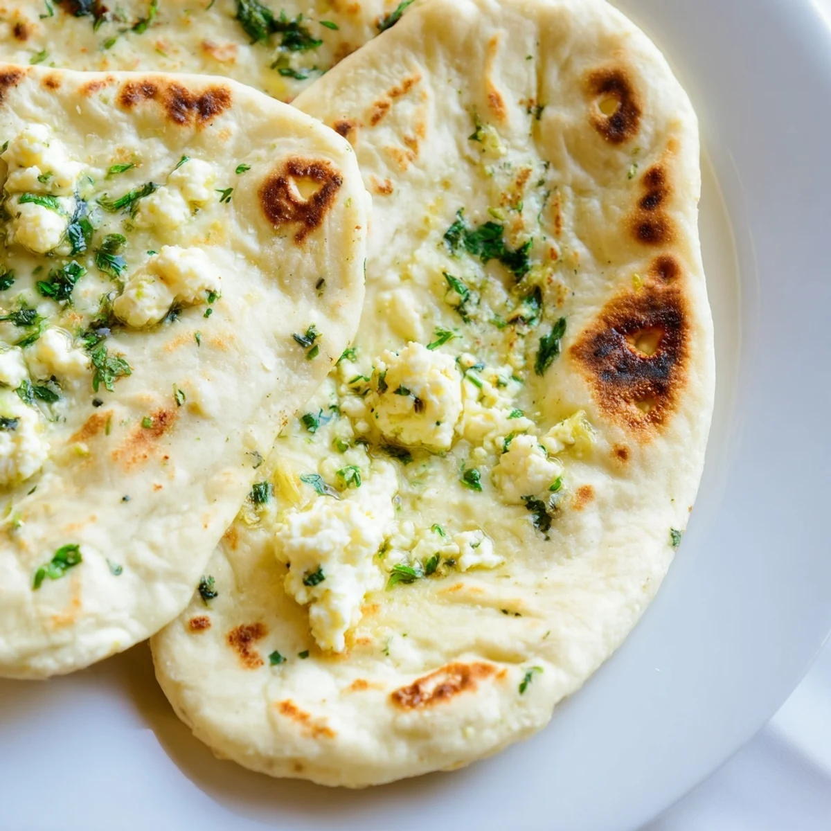 Warm Cottage Cheese Garlic Naan golden-spotted from a cast-iron skillet, garlic butter glistening, served hot for an authentic Indian meal experience.