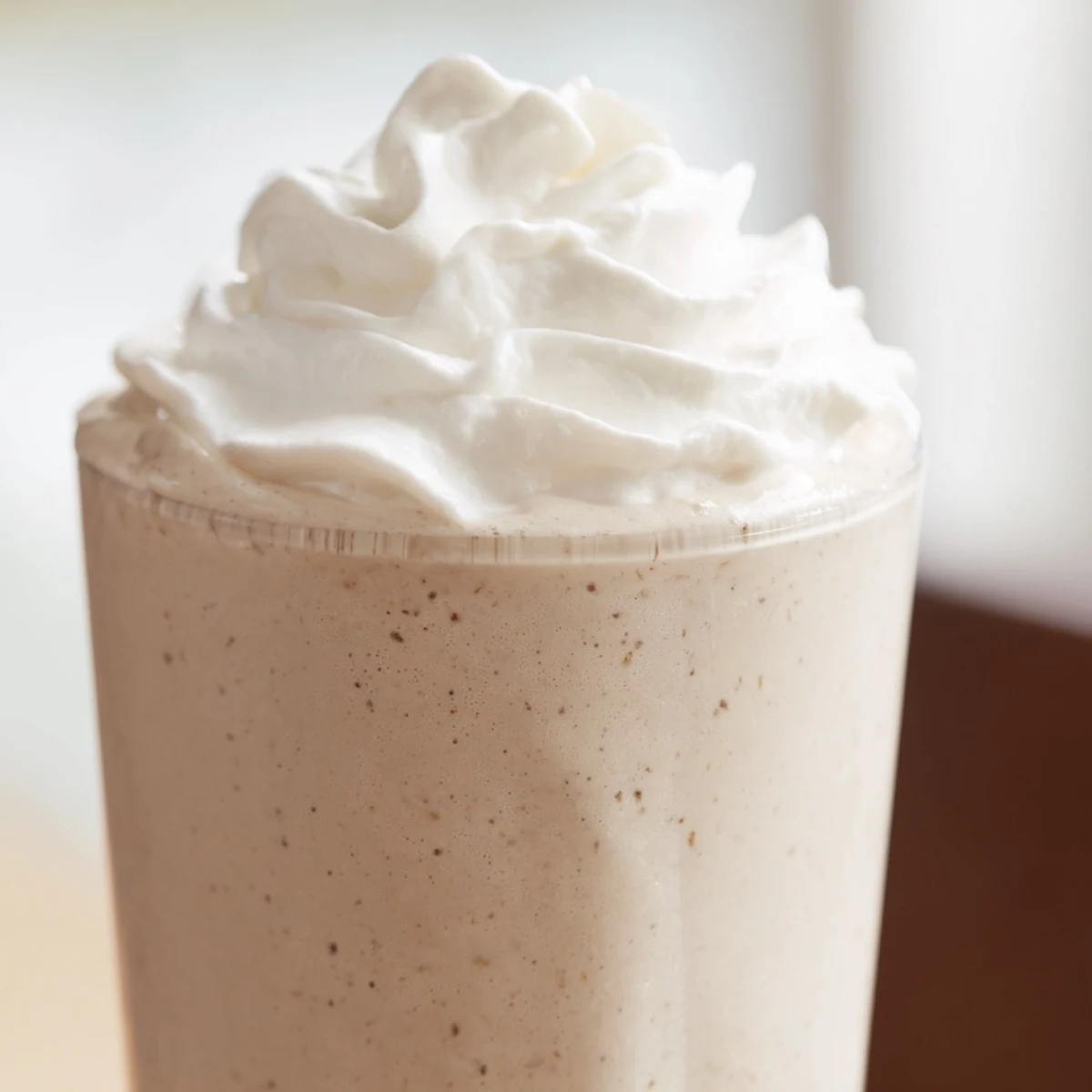 Two tall glasses of Starbucks Vanilla Bean Frappuccino topped with fluffy whipped cream and a straw.