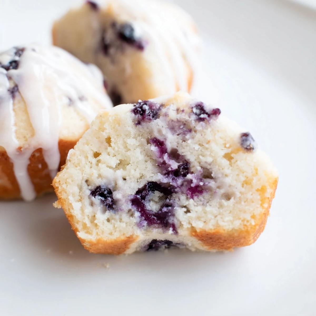 Individually portioned Lavender Blueberry Tea Cakes are arranged on a wire rack, perfect for an afternoon tea dessert serving.