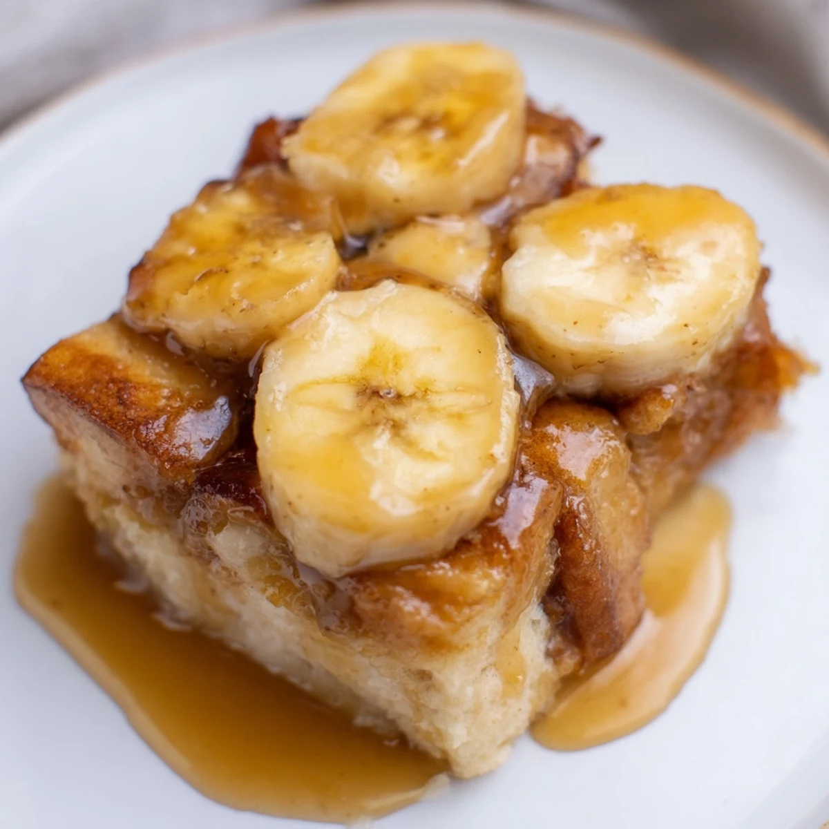 A close-up of Creamy Bananas Foster Bread Pudding, golden-brown and served with a scoop of vanilla ice cream.