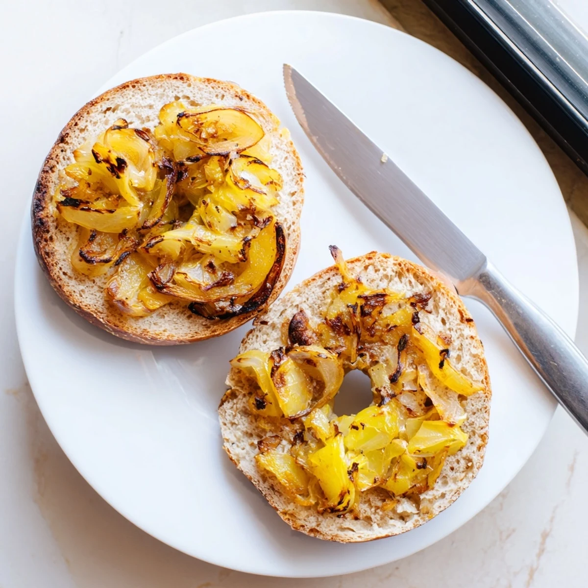 Tangy Sourdough Onion Bagels with a chewy interior and crispy crust, perfect for a hearty breakfast with cream cheese.