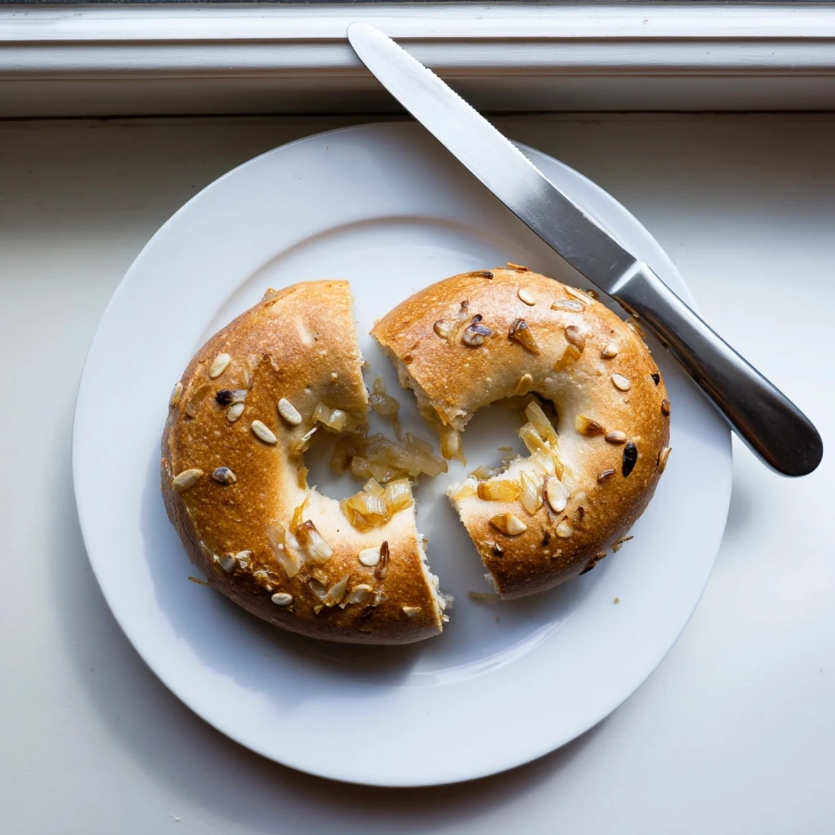 Eight freshly boiled and baked Sourdough Onion Bagels arranged on a wire rack, showcasing their glossy, onion-topped exterior.