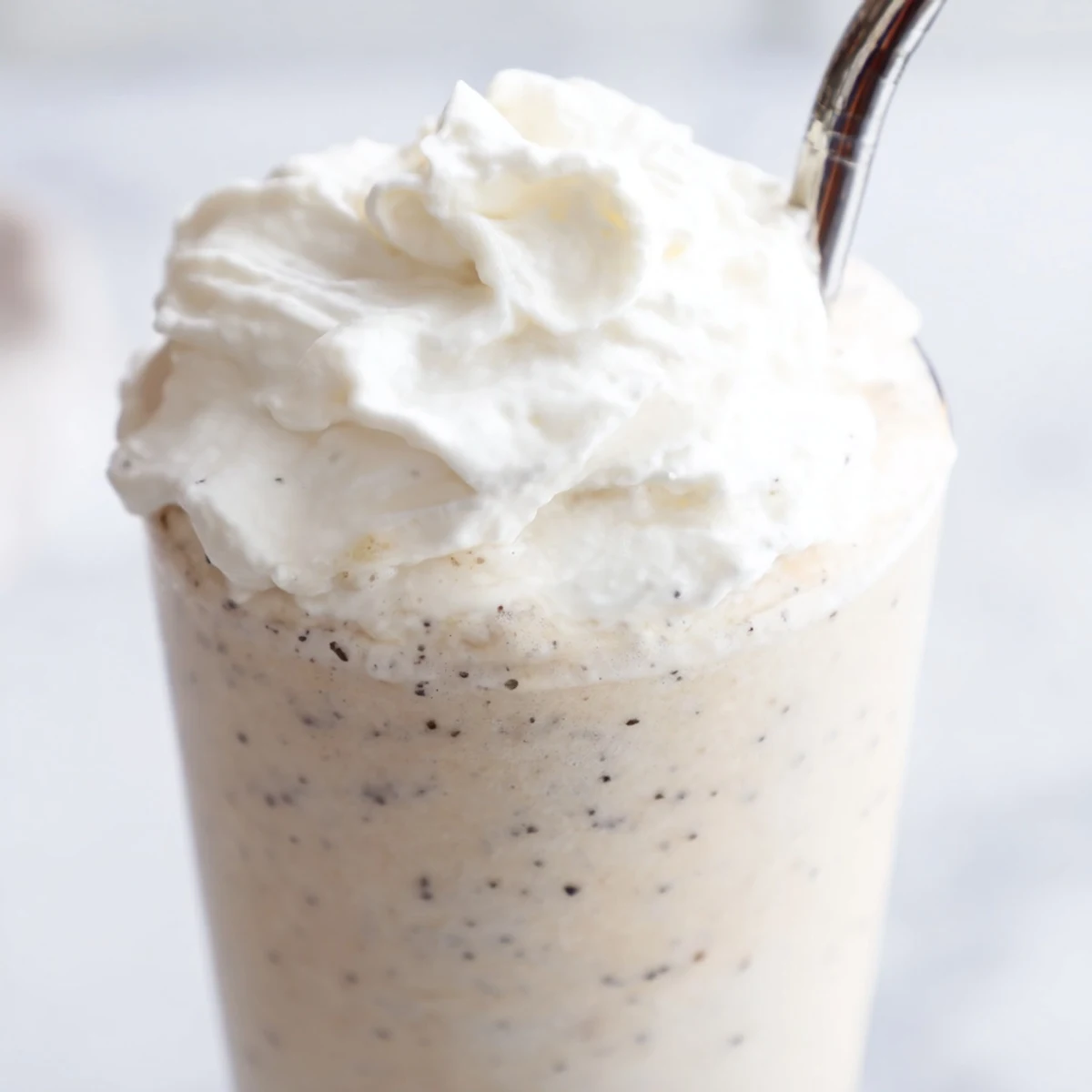 Homemade Vanilla Bean Frappuccino served over ice with a drizzle of whipped cream.