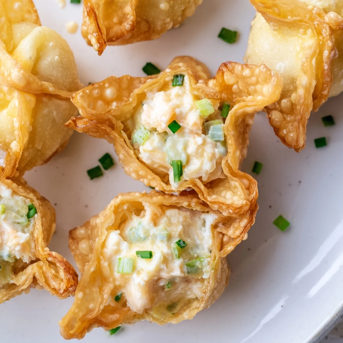 Delicious Crispy Crab Rangoon Bombs filled with creamy crab and cheese, garnished with fresh chives for a party appetizer.