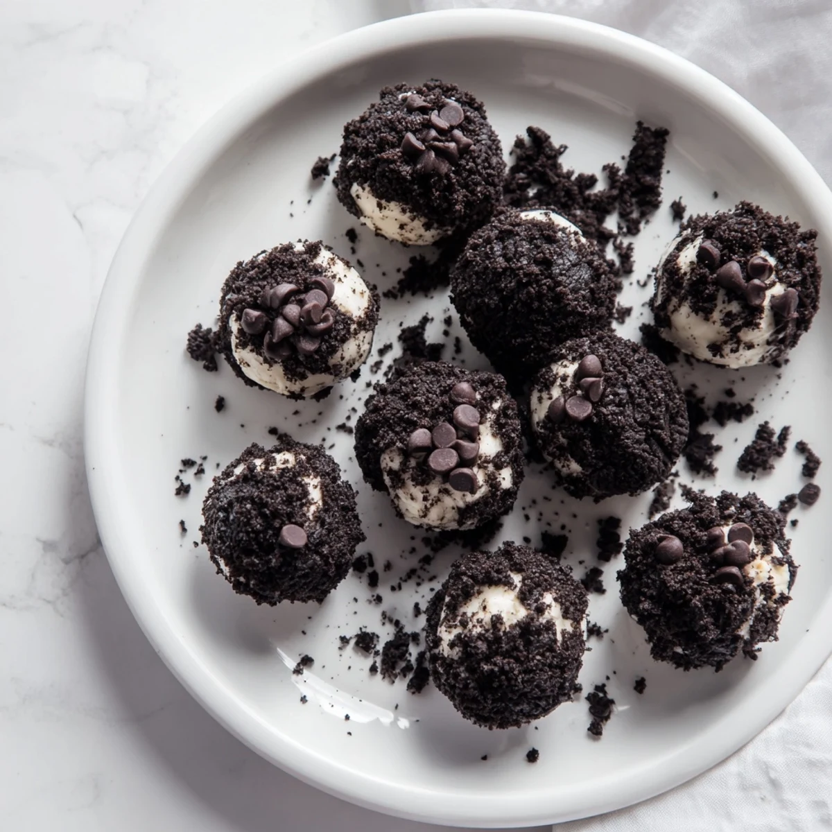 Cream Cheese Oreo Protein Balls arranged on a white plate with crumbs scattered around.