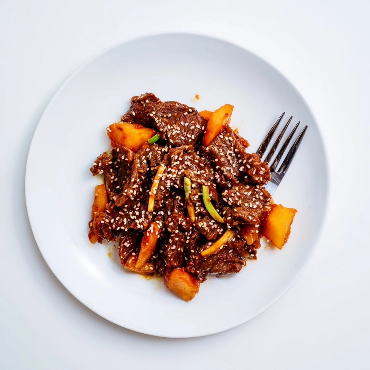 Savory Korean Style Pot Roast with meltingly tender beef chunks and vegetables on a white serving platter, steam rising.