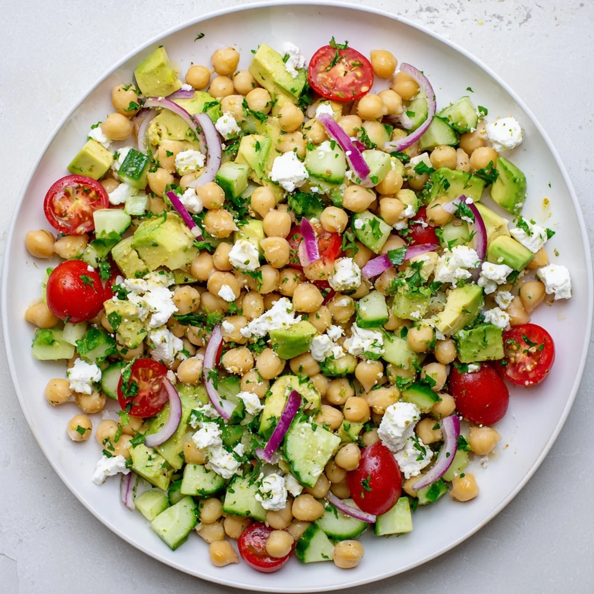 Serving suggestion for Chickpea Feta Avocado Salad with fresh parsley garnish, ready to eat on a plate with optional pita bread.