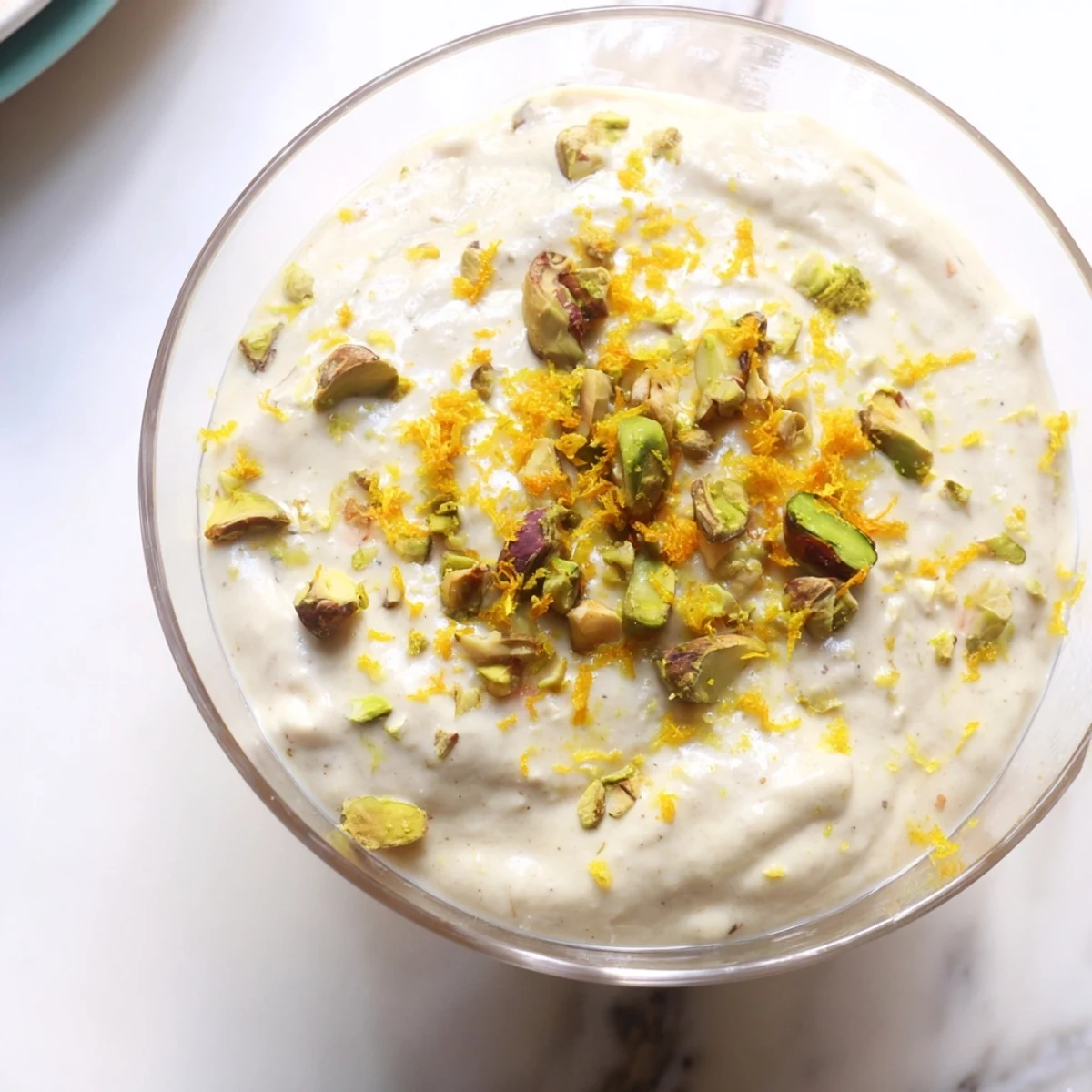 Airy Lebanese Date Orange Blossom Mousse topped with crushed pistachios and orange zest in a glass.