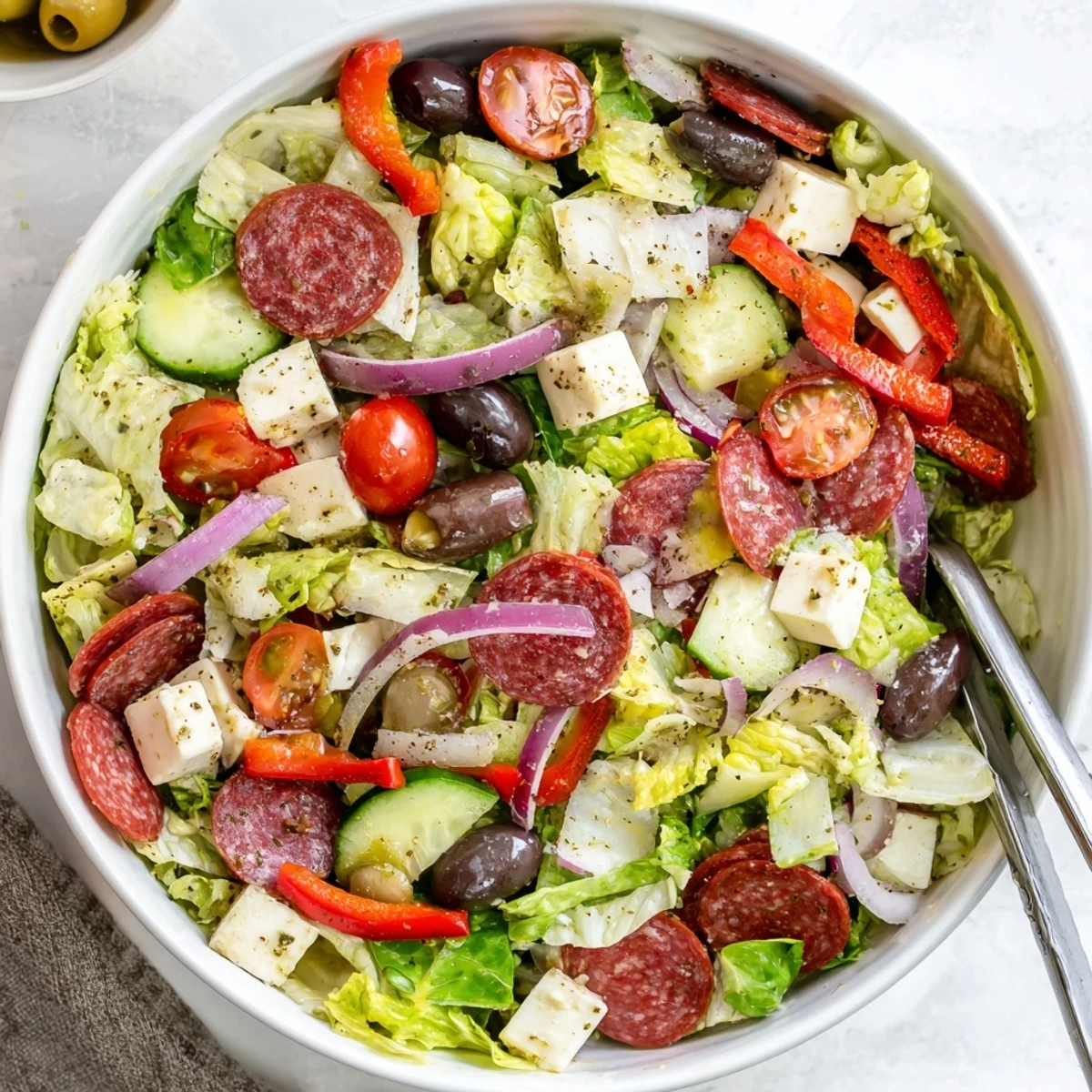 Colorful Italian chopped salad with fresh romaine, tomatoes, salami, olives, and tangy homemade dressing