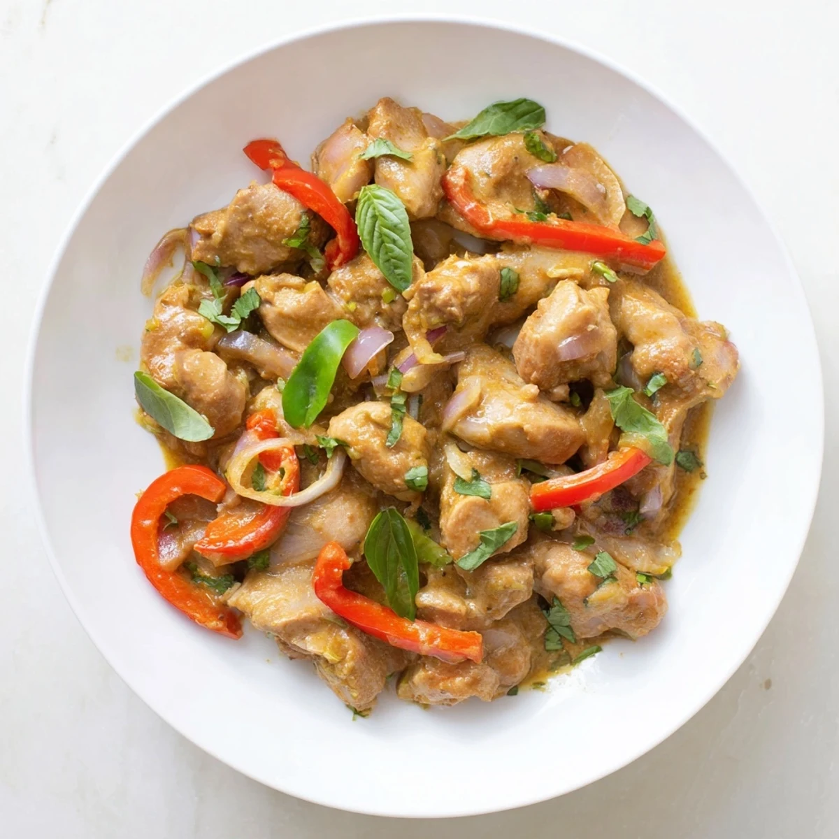 Creamy coconut curry with tender chicken pieces garnished with fresh basil leaves