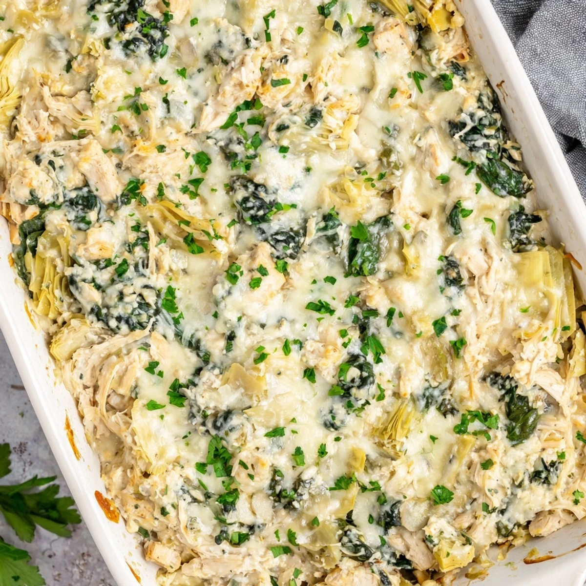 Golden bubbly high protein spinach and artichoke chicken casserole fresh from the oven with melted cheese topping