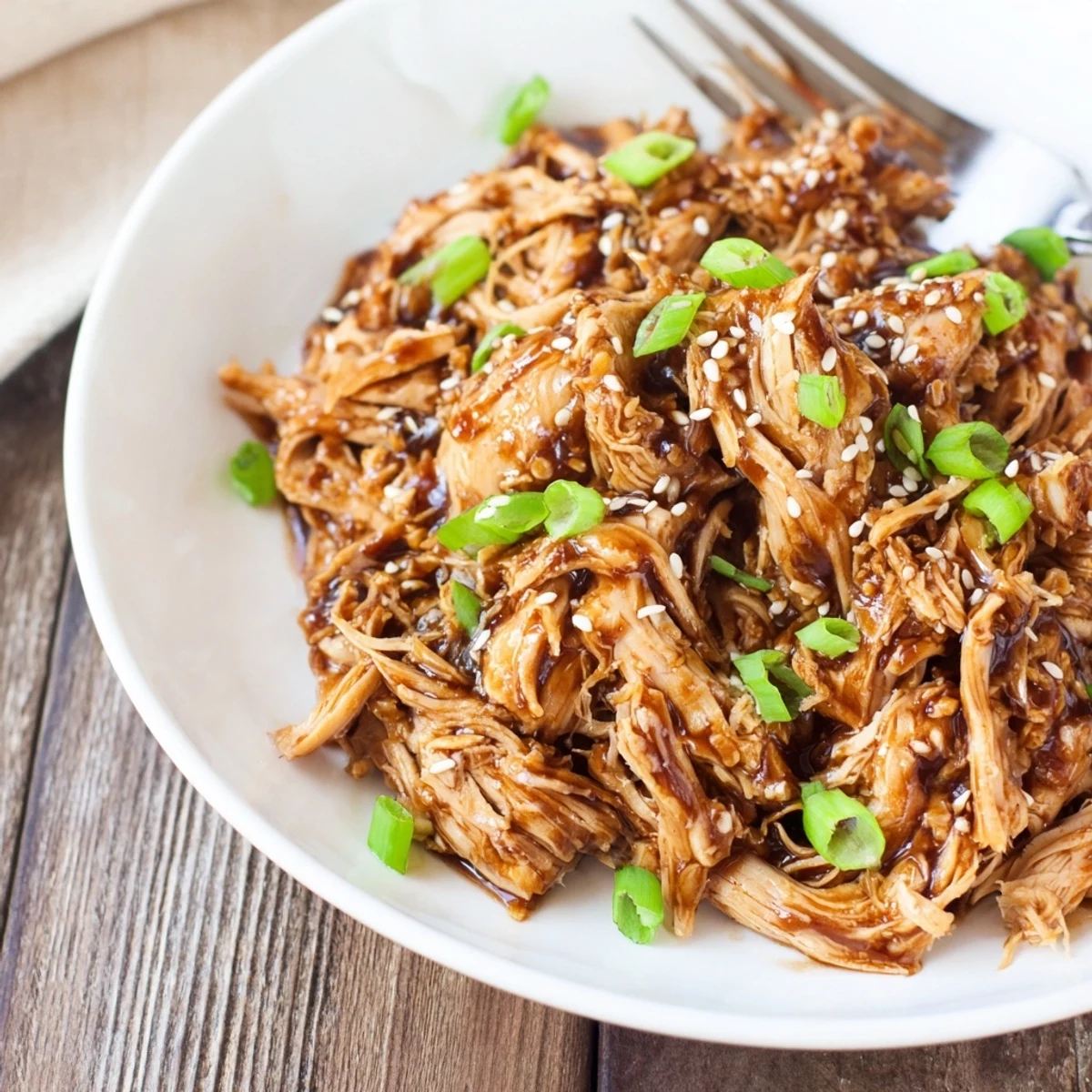 Easy slow cooker Mongolian chicken served over steamed jasmine rice with caramelized edges and fresh chopped scallion garnish