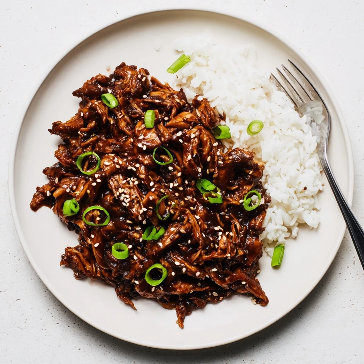 Golden brown slow cooker Mongolian chicken glazed in thick sweet savory sauce with green onions