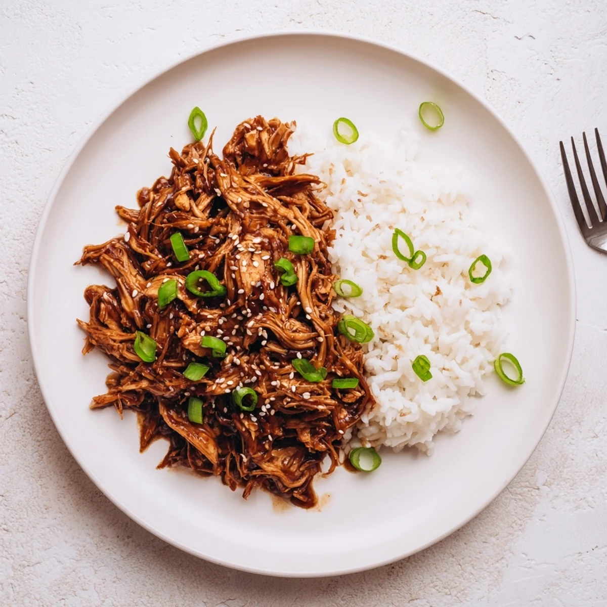 Tender shredded Mongolian chicken pieces coated in rich hoisin honey sauce over fluffy white rice
