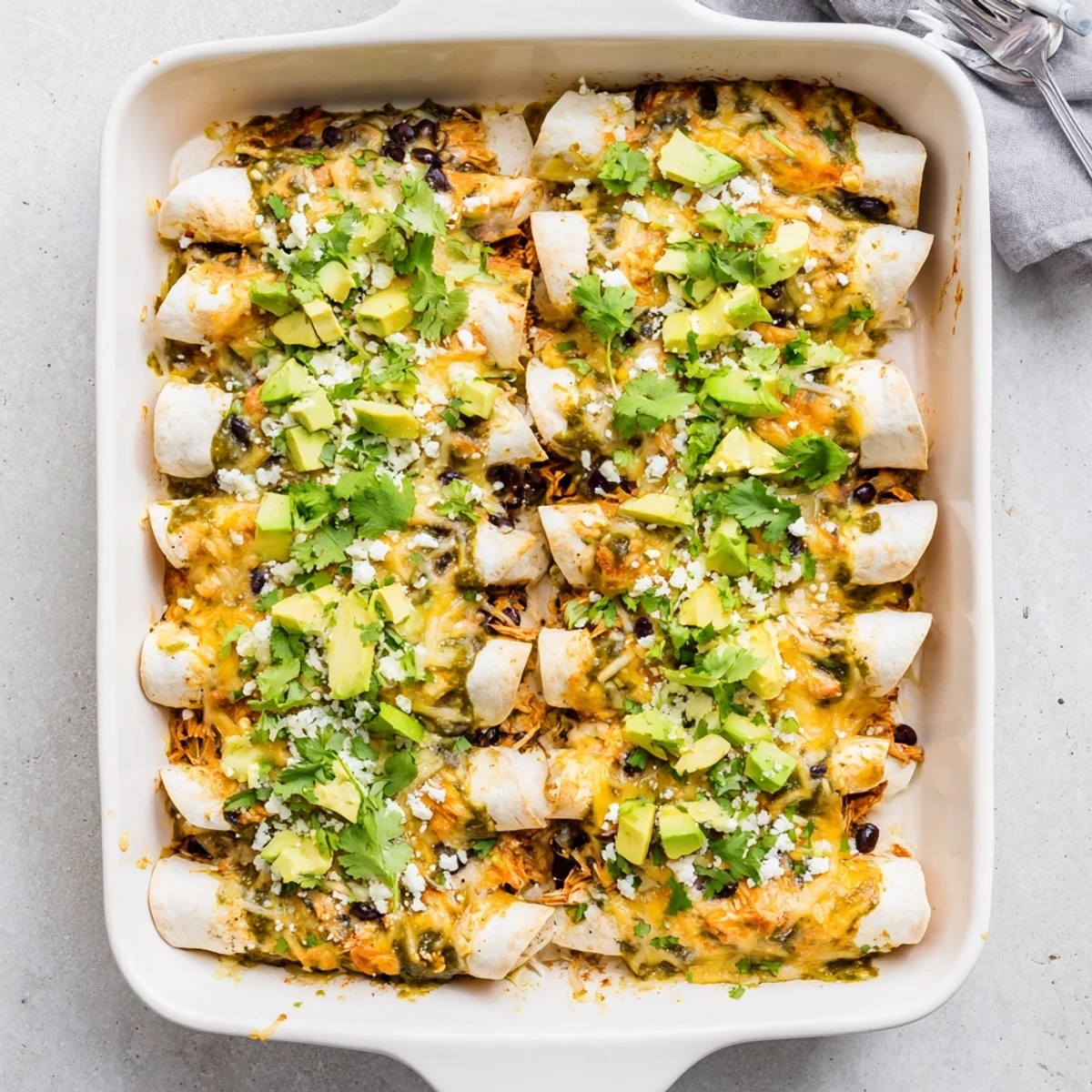 Golden baked salsa verde chicken enchiladas topped with melted Monterey Jack cheese and garnished with fresh cilantro