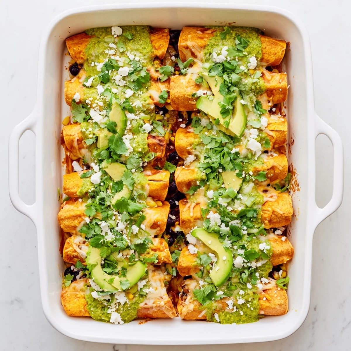 Bubbling hot salsa verde chicken enchiladas with melted cheese ready to serve with diced avocado and lime wedges