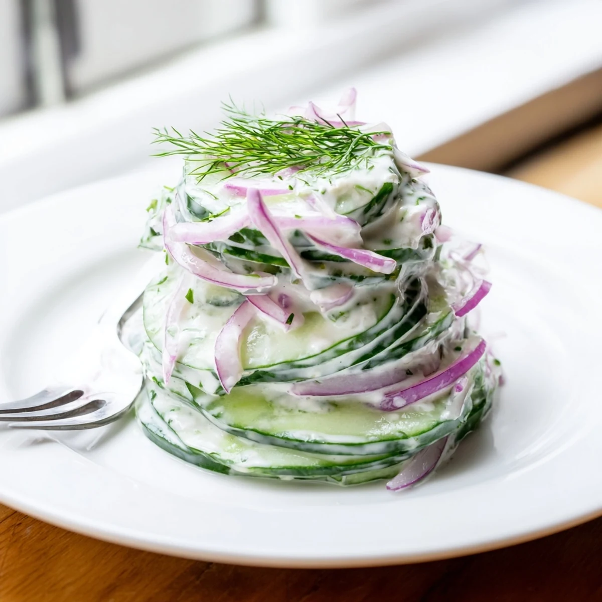 Creamy cucumber salad with crisp red onion slices on white plate for summer meal