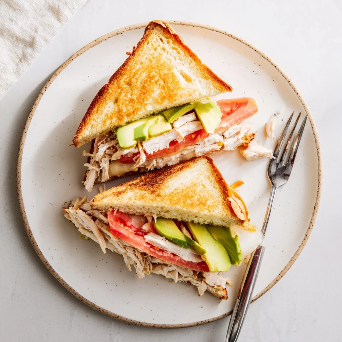 Golden grilled chicken avocado melt sandwich with melted provolone on toasted sourdough bread