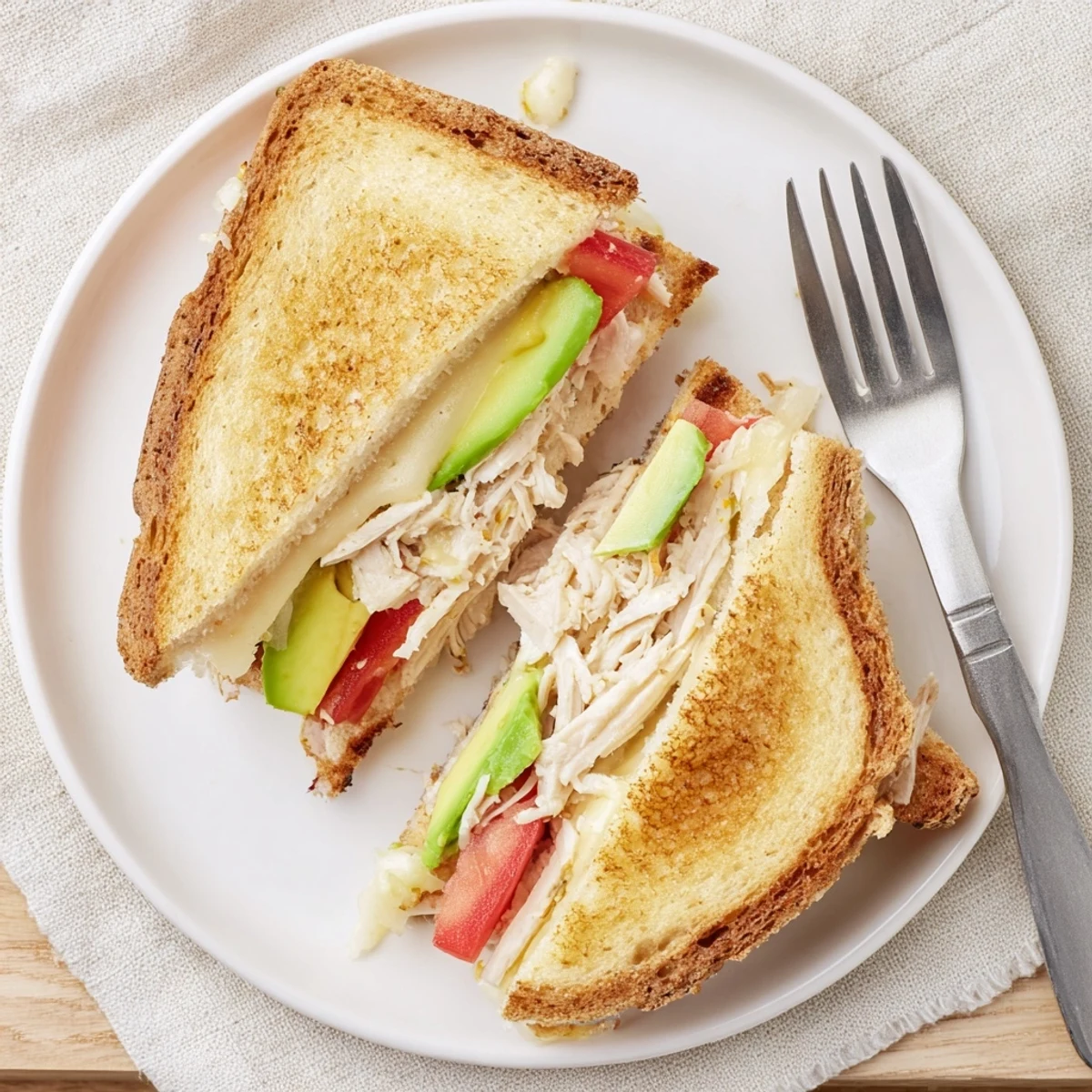 Warm chicken avocado melt on a wooden board with fresh cilantro garnish and melted cheese