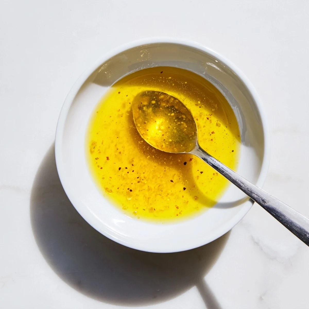 Bright tangy dressing spooned over green salad with cherry tomatoes on wooden board