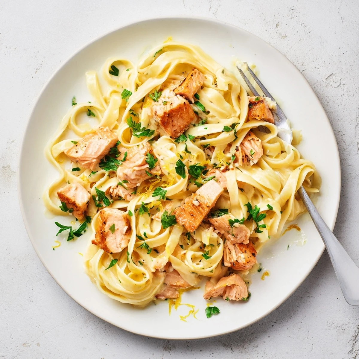 Golden seared salmon flakes resting atop creamy garlic butter fettuccine pasta with fresh parsley