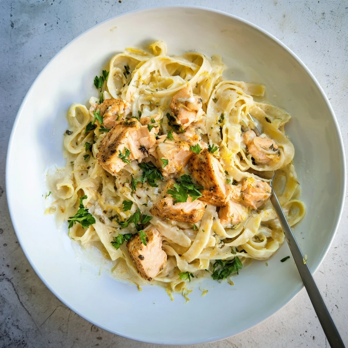 Elegant pasta dish featuring fettuccine tossed with parmesan cream sauce and buttery seared salmon fillets