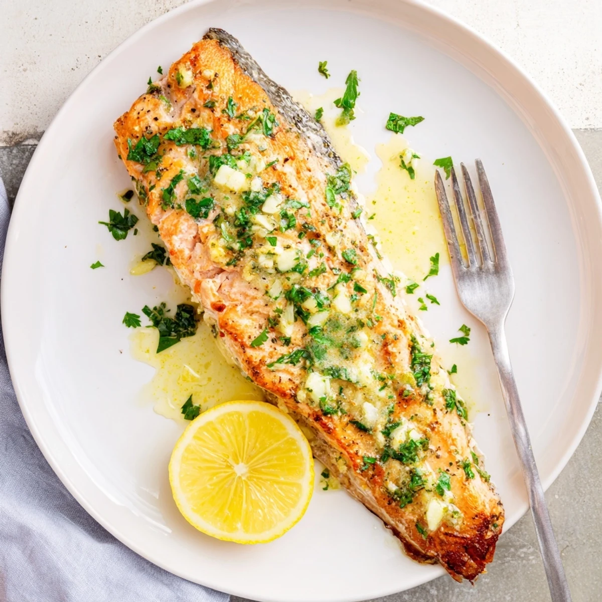 Golden pan seared salmon fillets glistening with melted garlic butter sauce and fresh parsley
